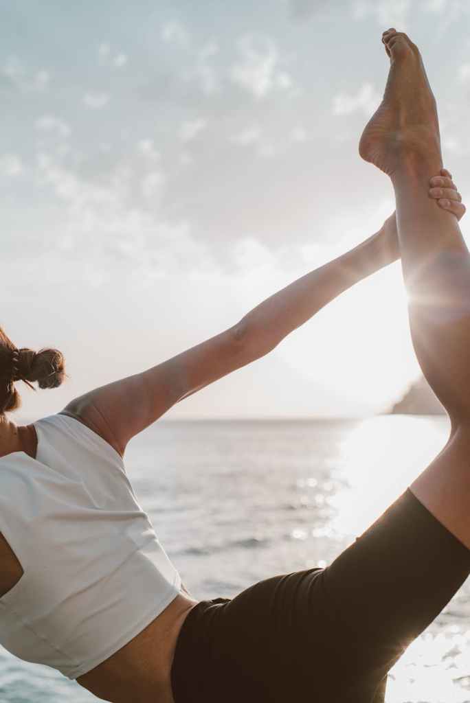 a woman doing yoga near the ocean